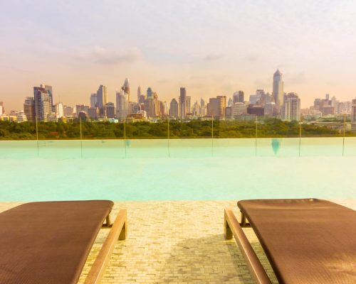 Chair around outdoor swimming pool with city view - Vintage Filter